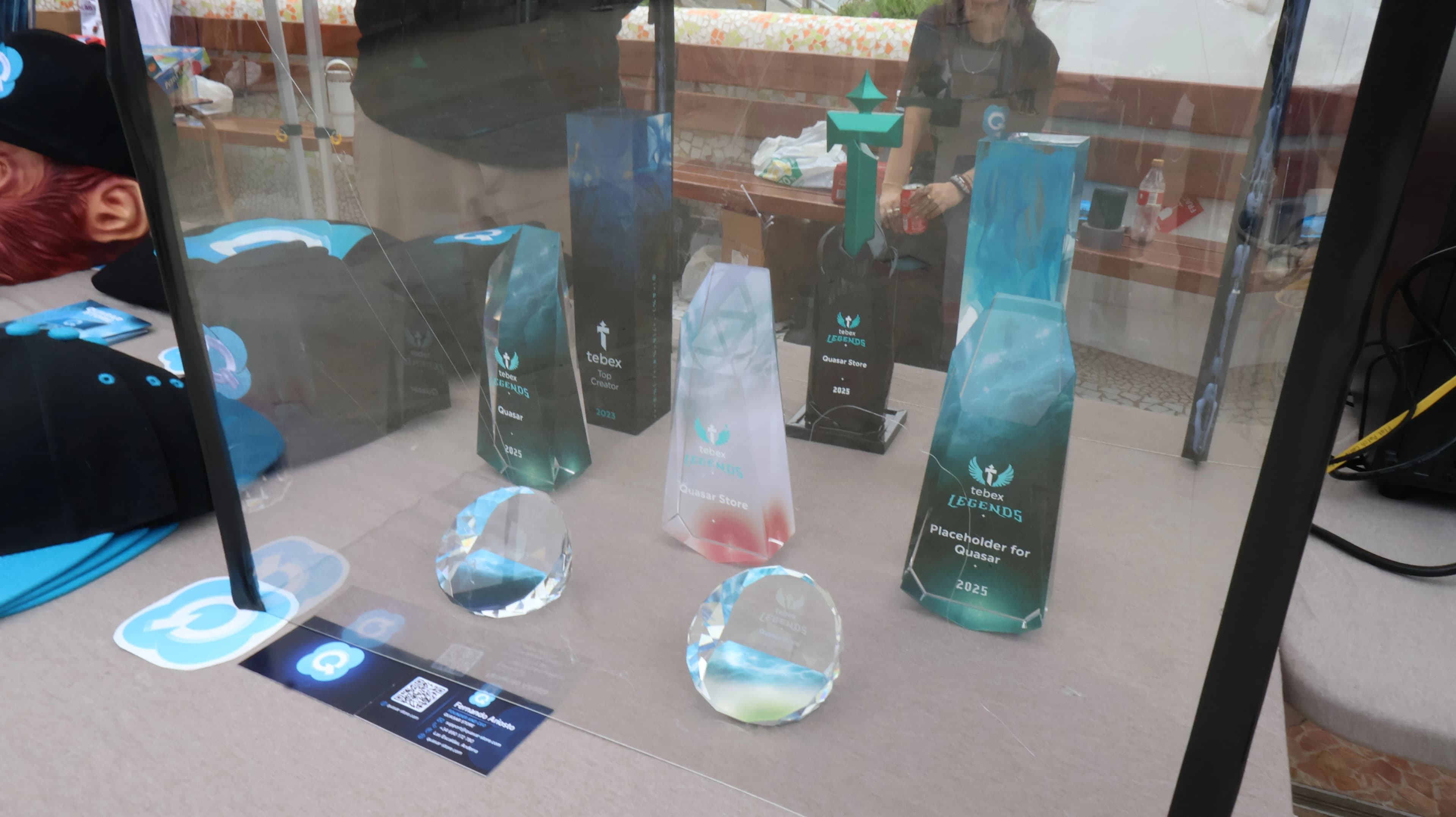 Quasar Store booth displaying Tebex and Cfx.re award trophies alongside official merchandise